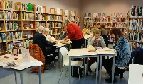 mehrere Tische mit 2-4 Personen besetzt, Teilnehmer unterhalten sich über die Bücher